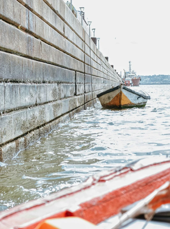 two small boats floating in the water near wall