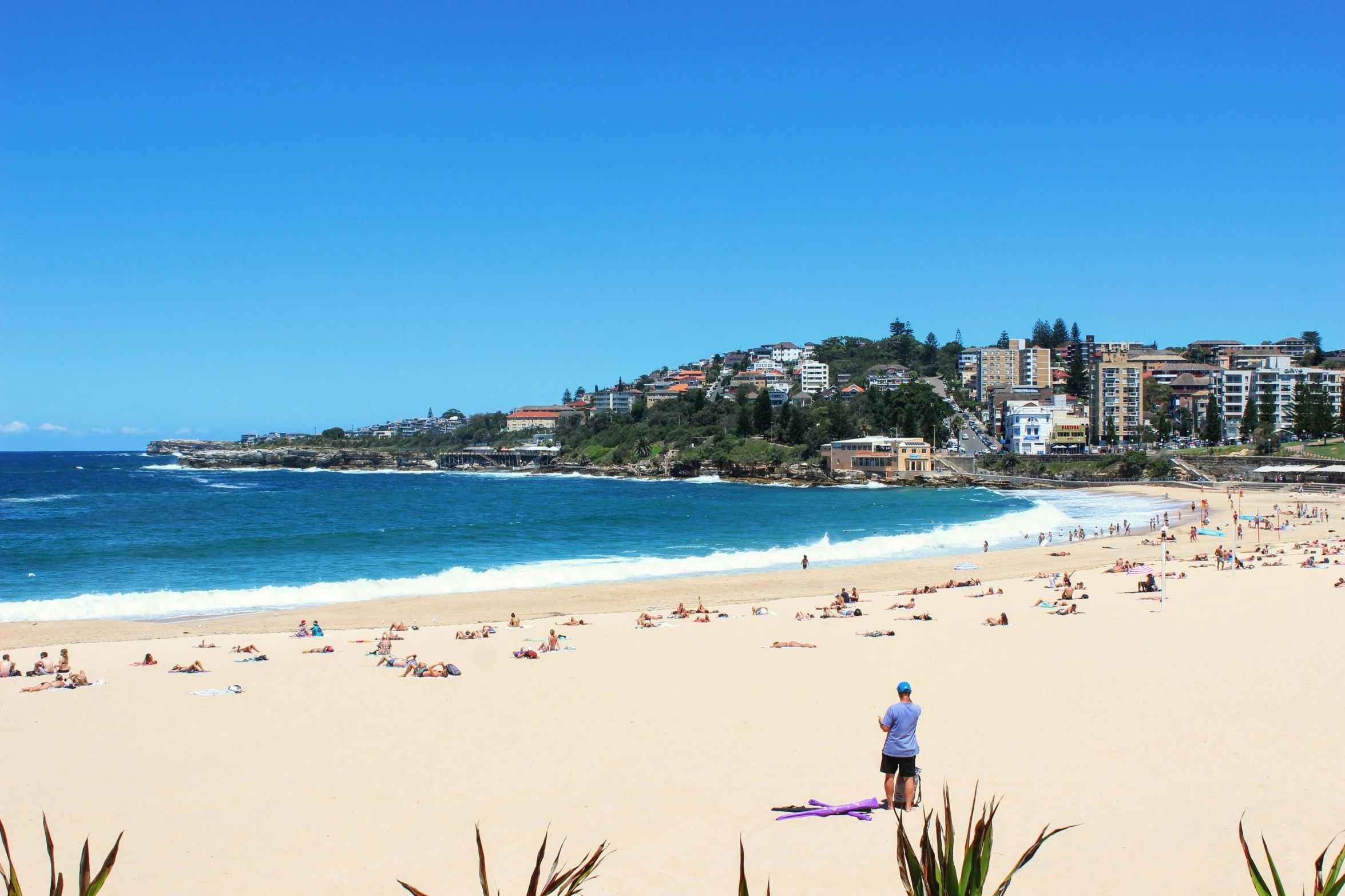 the man is standing on a surfboard near a crowd of people