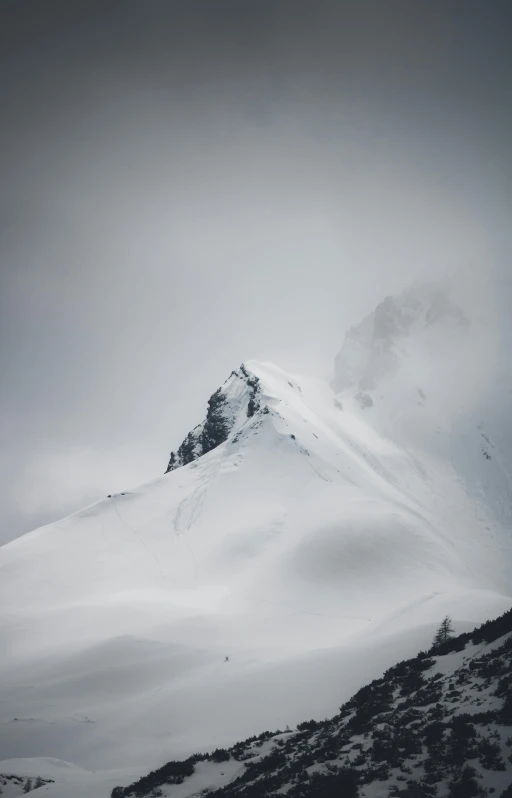 a very tall snow covered mountain on a cloudy day