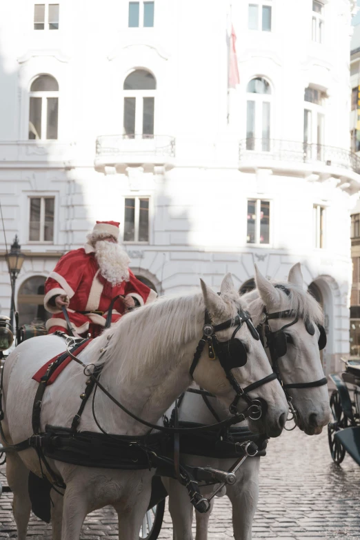 santa claus rides a horse drawn carriage on cobblestone