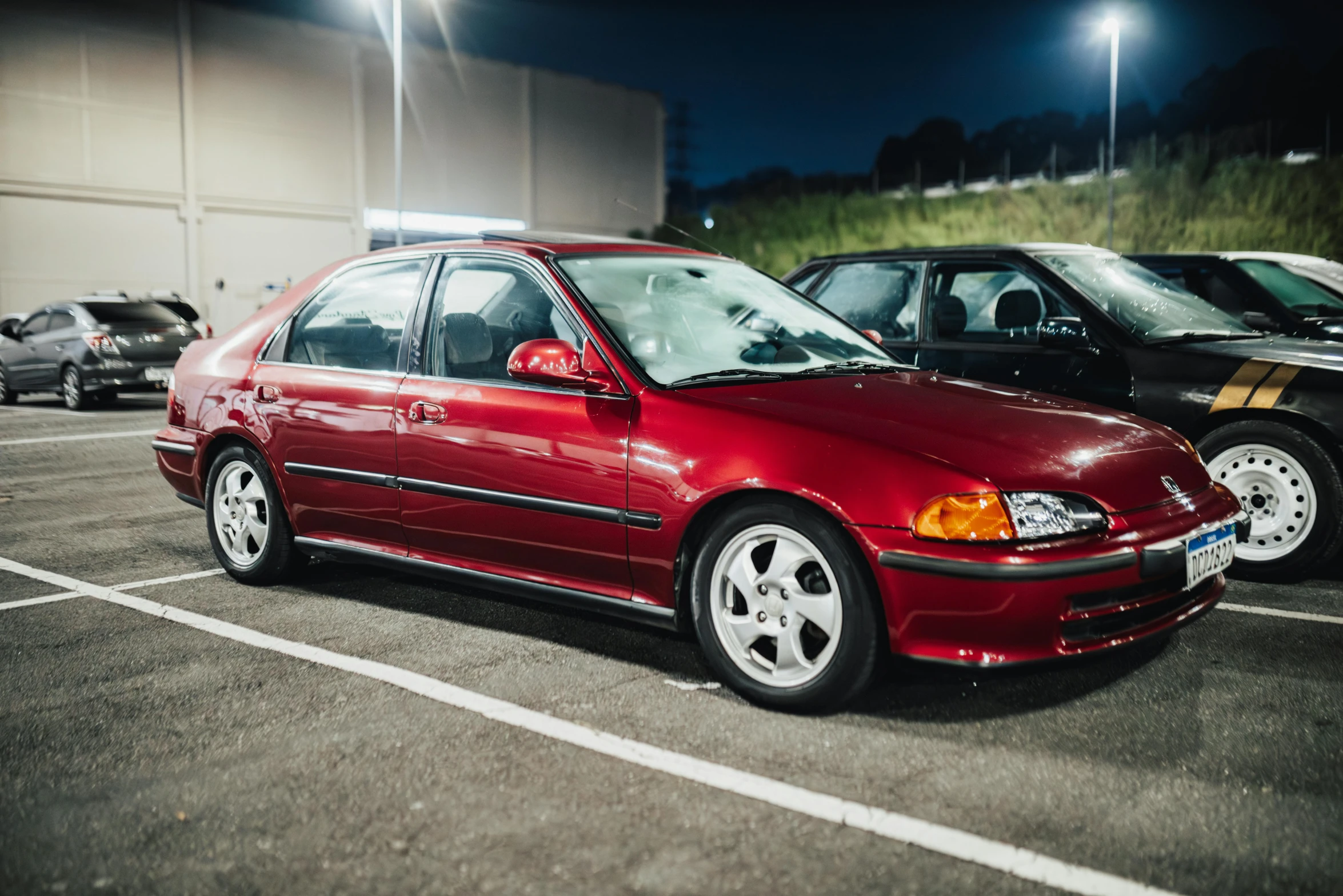 a red car parked next to other cars in a parking lot