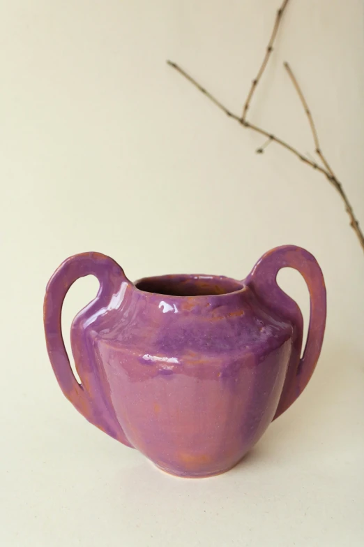 a purple pottery pitcher on top of a white table