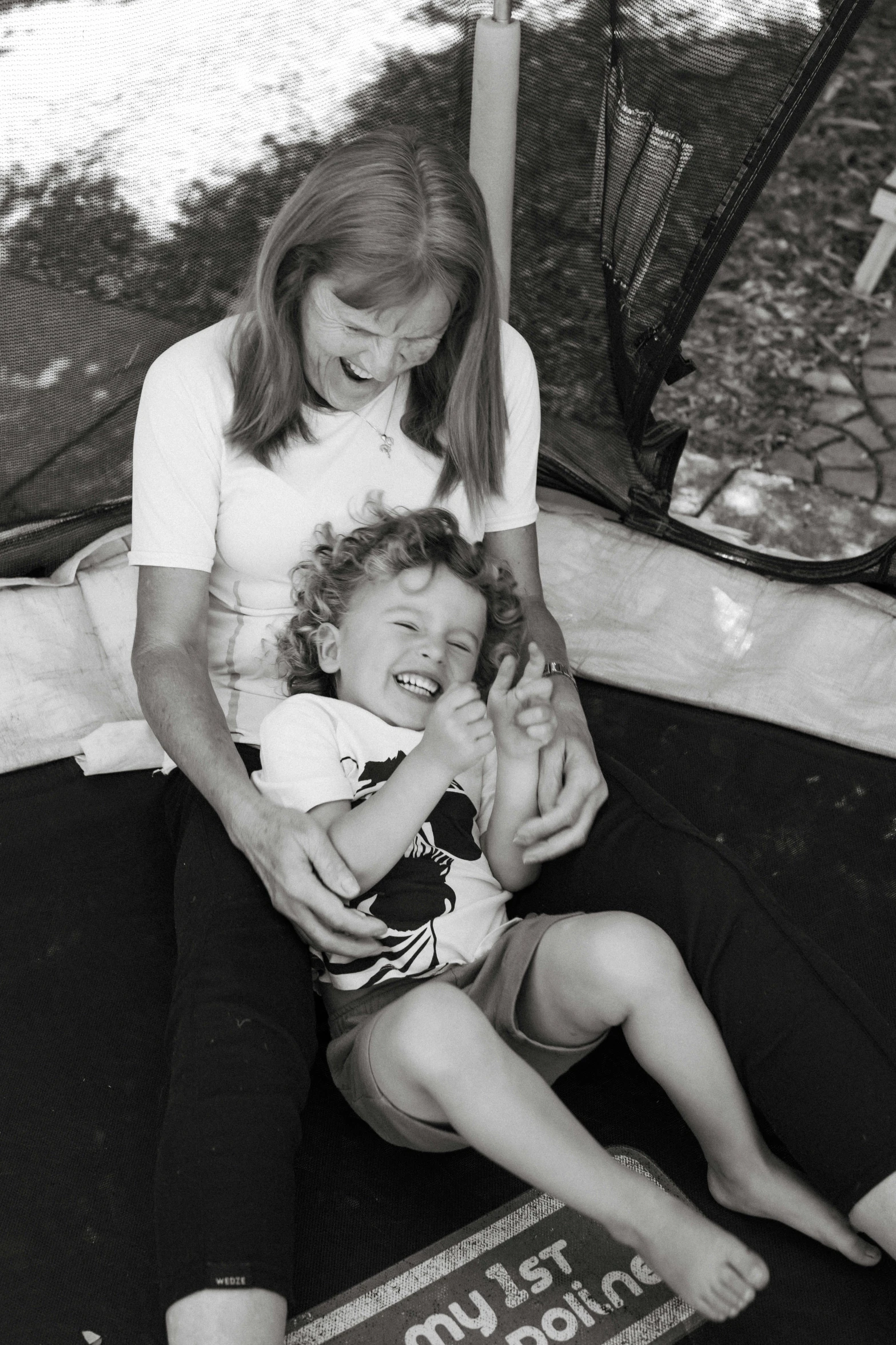 a woman holding a little boy next to a mesh net