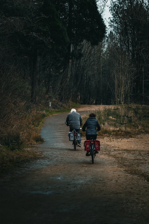 two people riding bikes down a narrow road