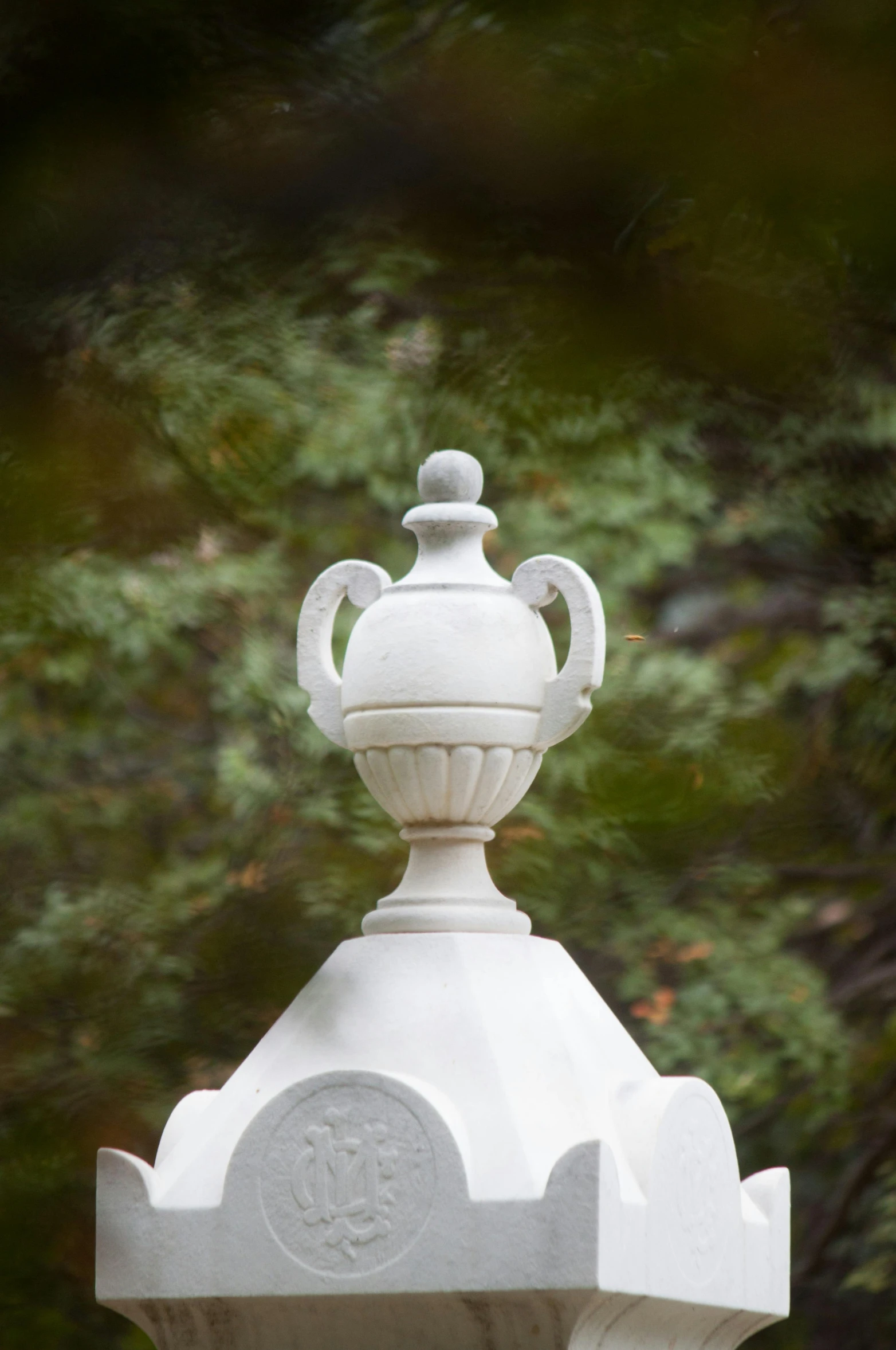 a white statue surrounded by green trees