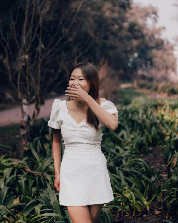 woman covering face with her hands standing in front of grass