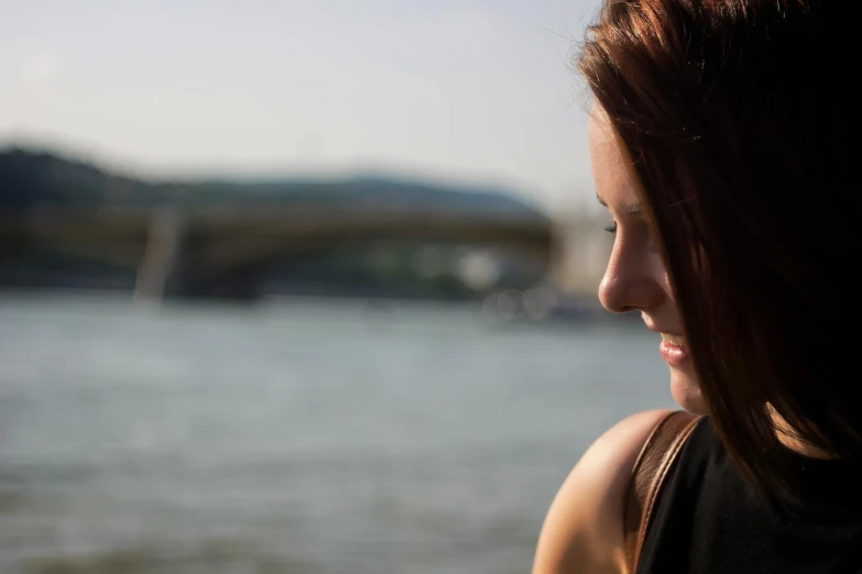 a woman standing in front of the water in a park