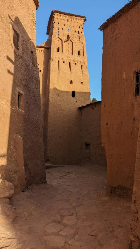 a path between two adobe buildings is shown
