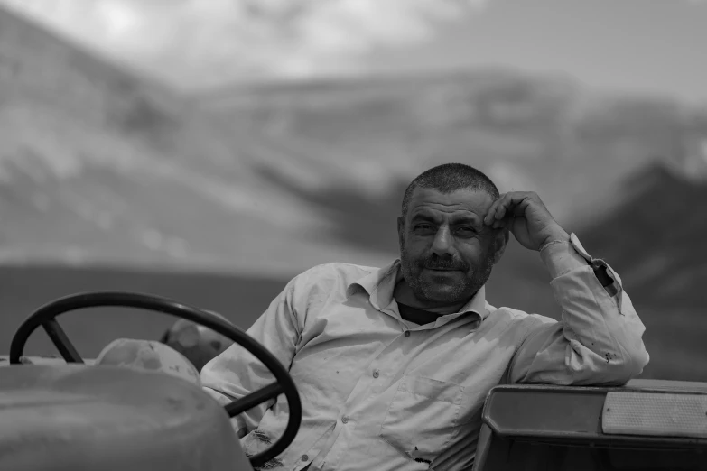 black and white po of a man sitting in an antique car