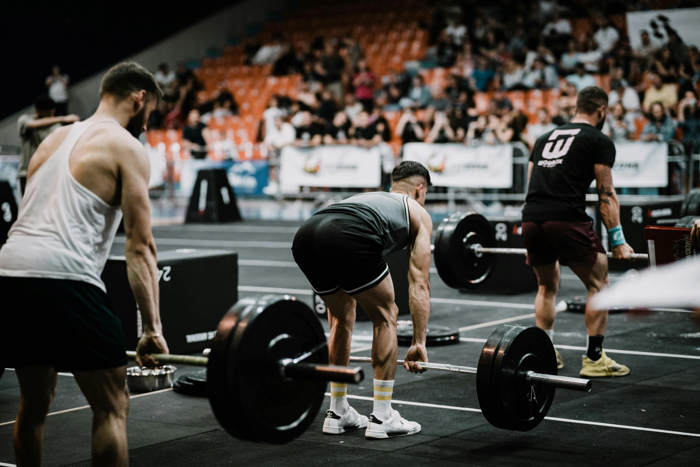 three men working out with barbells at a gym