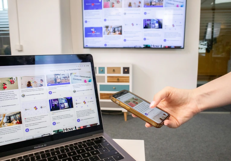 a laptop is open while someone holds an iphone