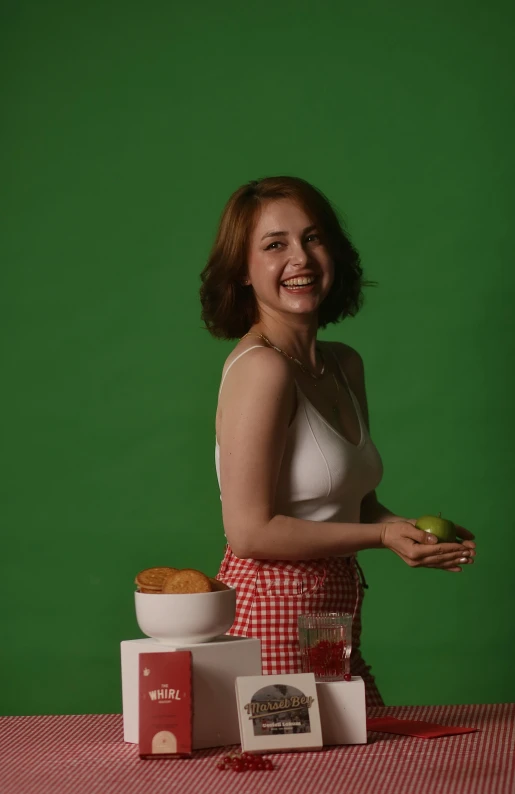 a young woman poses for a pograph with several fruit in front of her