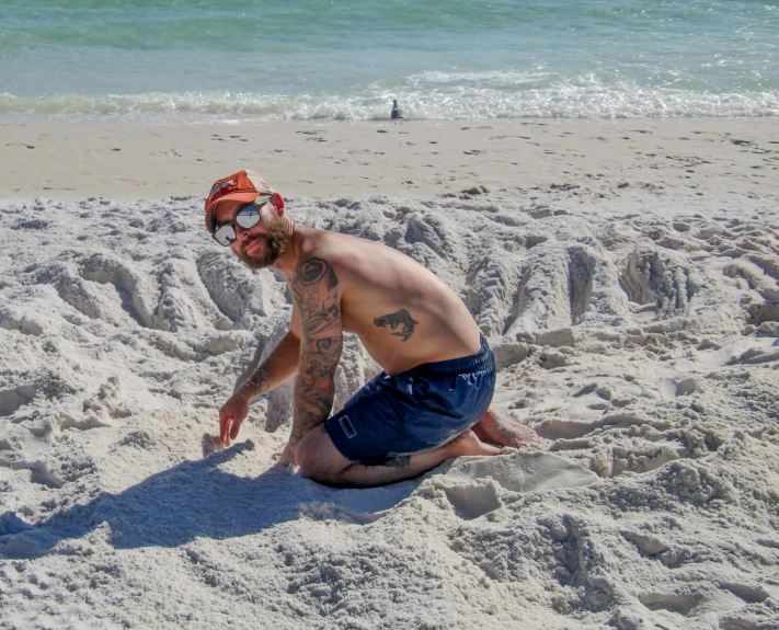 a man on the beach has his hand in the sand while sitting