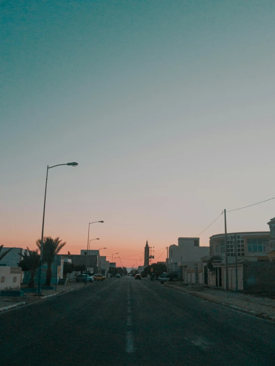 a dusk street with buildings and some lights