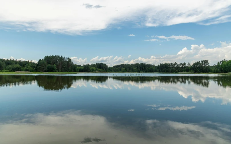 a lake with several birds in it and some clouds in the sky