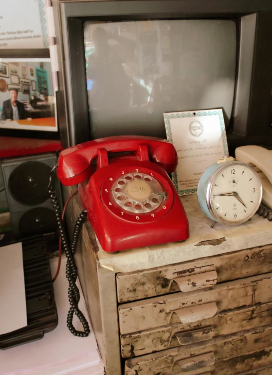 an old phone and clock on a dresser