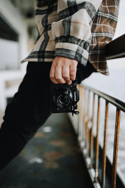 a person holding onto a camera that is being held over a rail