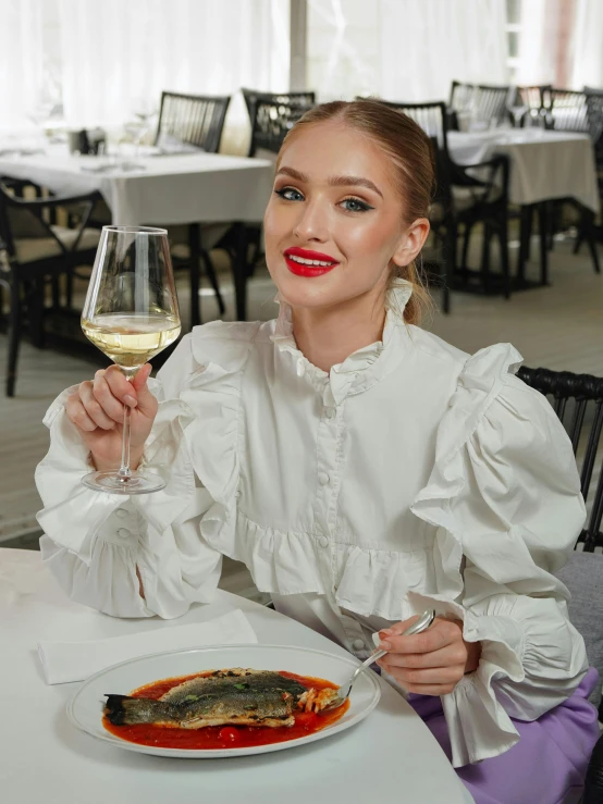 woman holding a glass of wine and looking to the camera