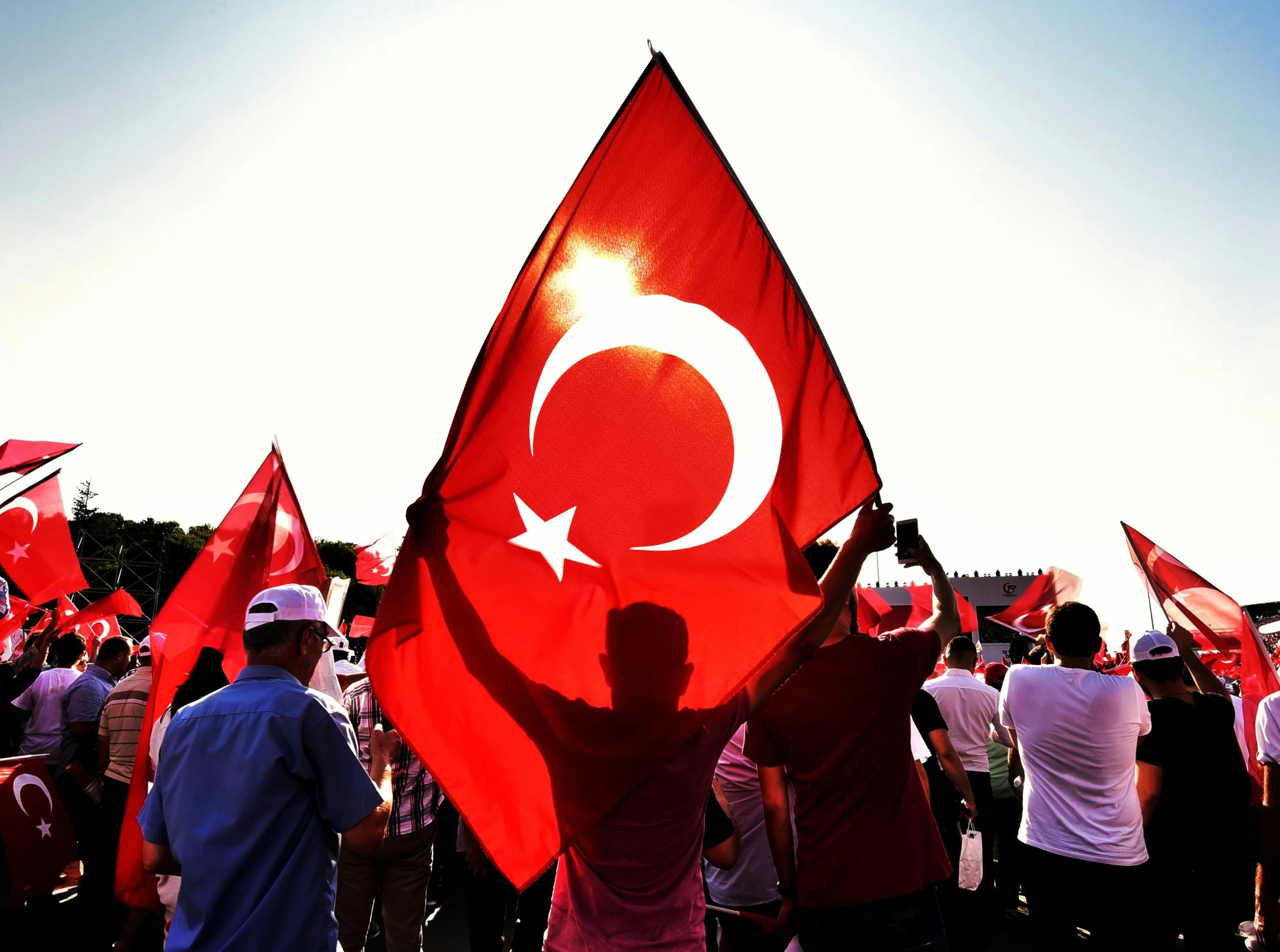 a crowd of people holding flags and talking on cellphones