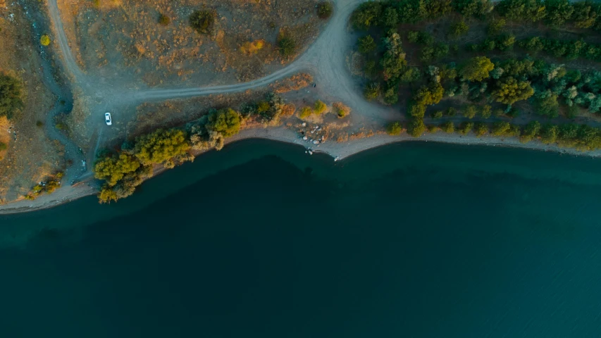 an aerial view of water and land with a road