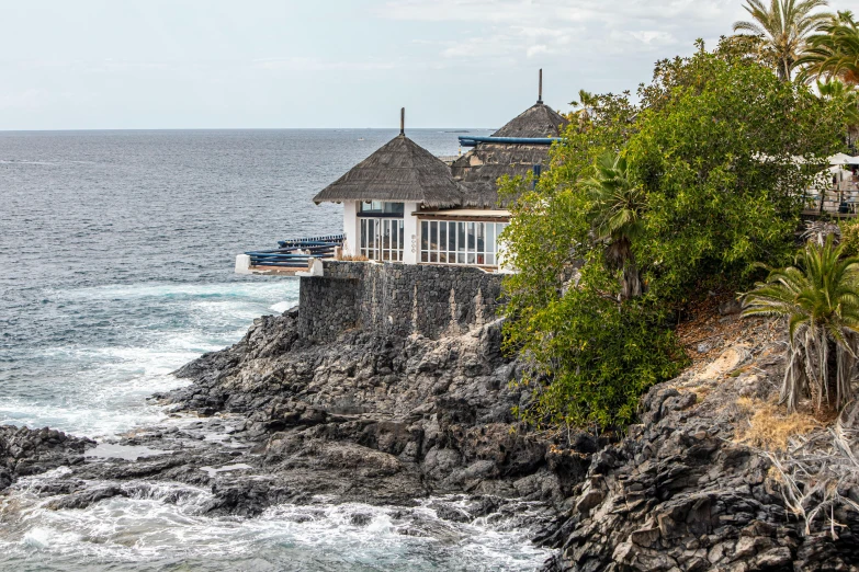 a house on the cliff next to the ocean