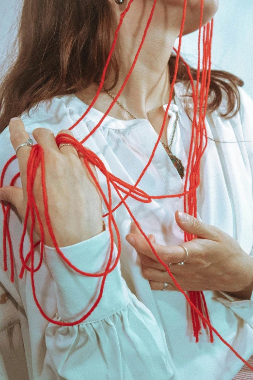 a woman is wearing red thread in her hand