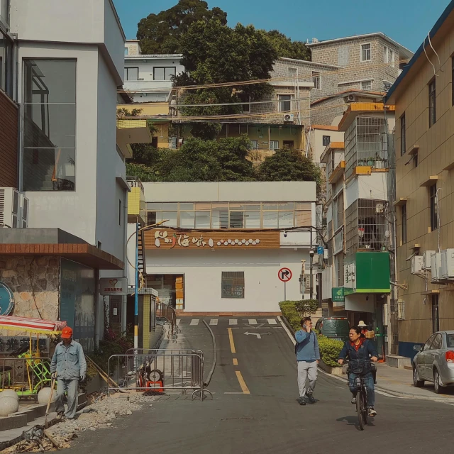 two bicyclists riding on a city street, with the buildings behind them