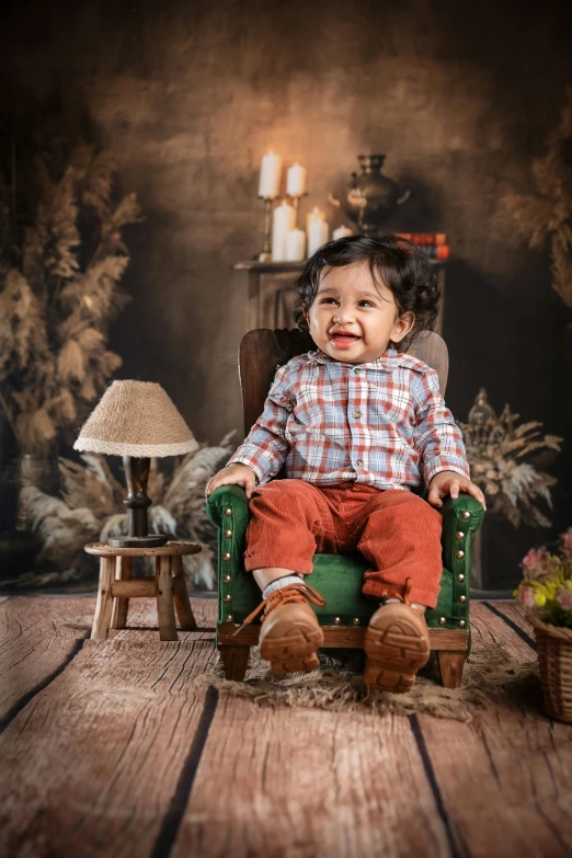 a toddler sitting on an old green chair in front of a fireplace