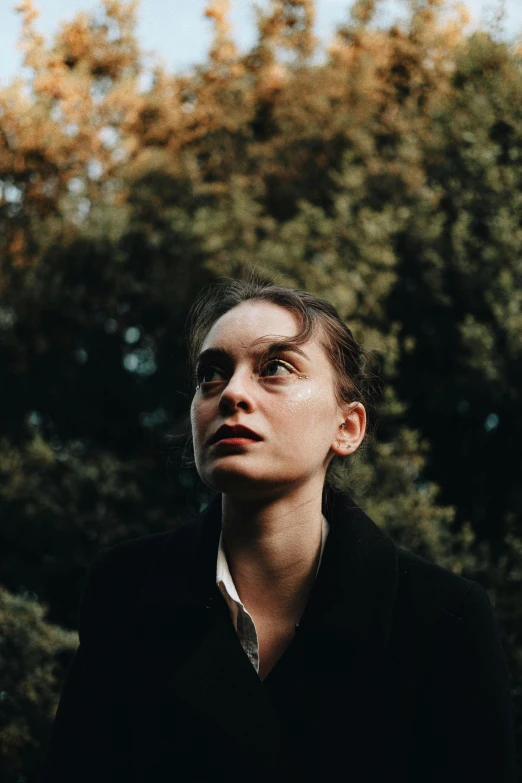 a woman standing in front of trees looking up