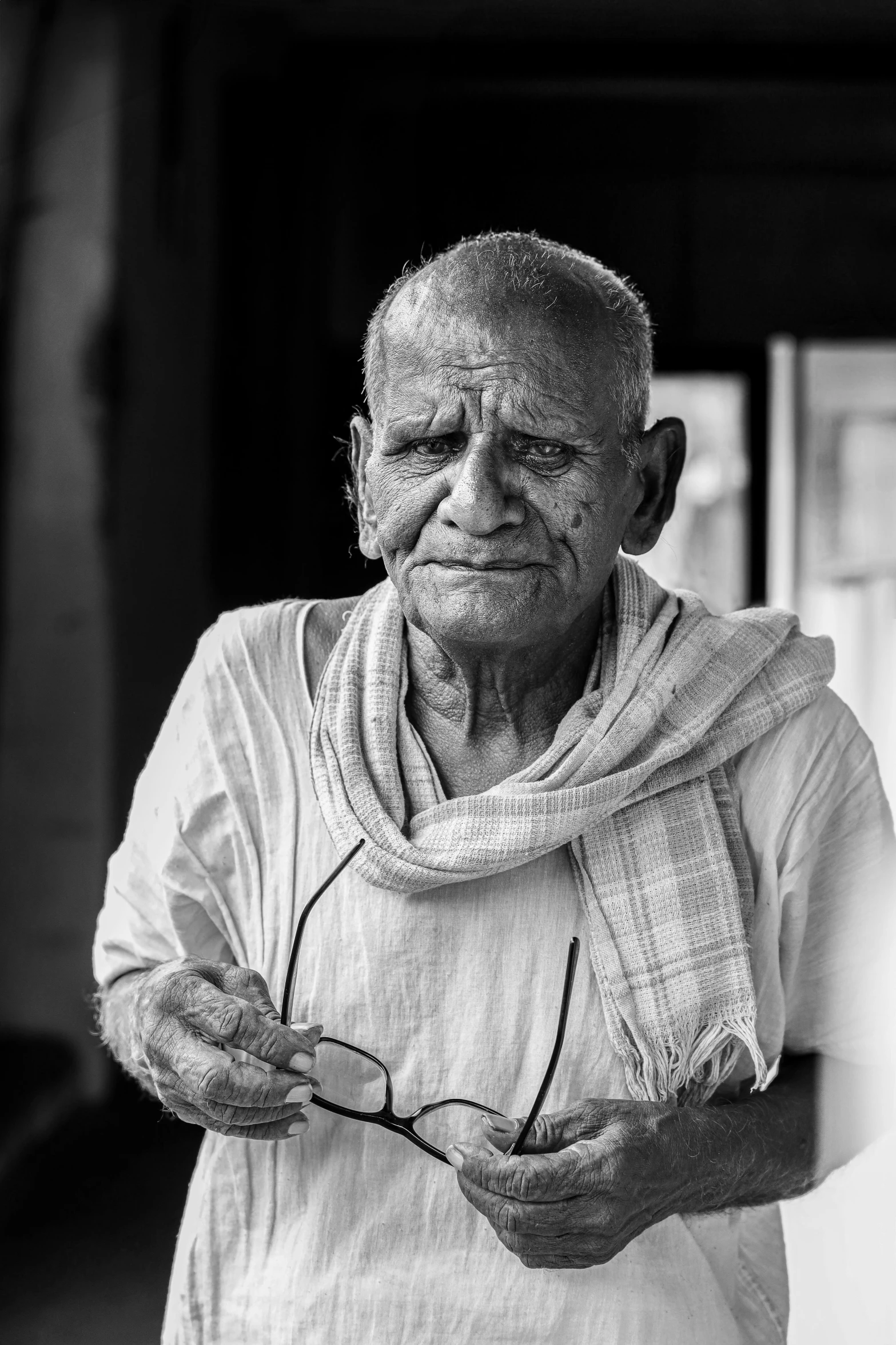 an elderly man holds up soing with a cloth on his chest