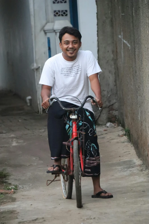 the man rides his bike down the narrow street