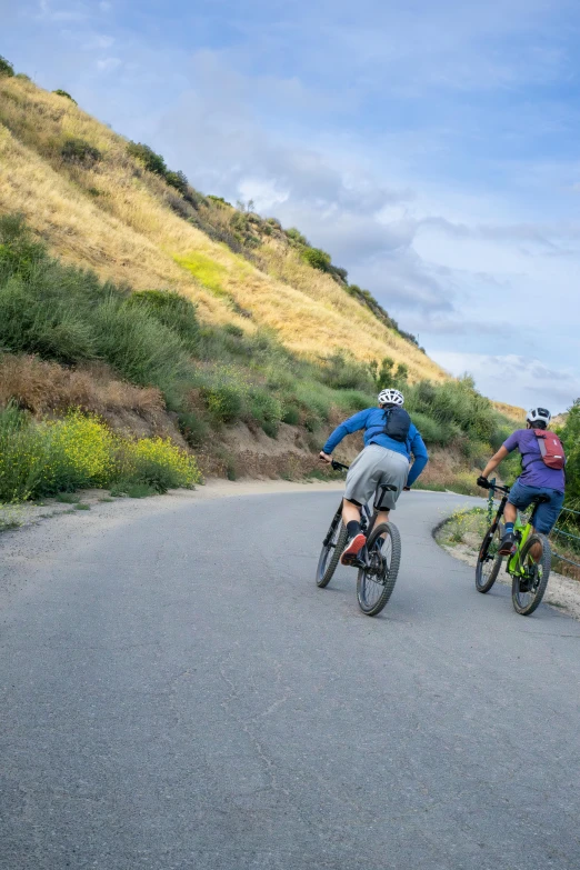 people on bicycles going down a mountain side road