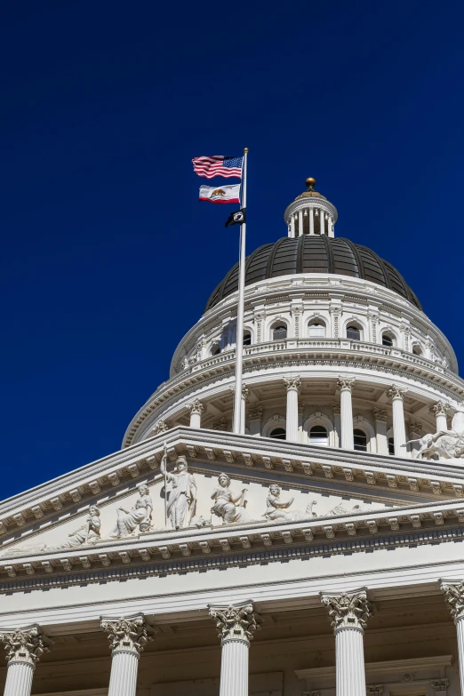 the top of the capitol building with columns, and a flag flying on it