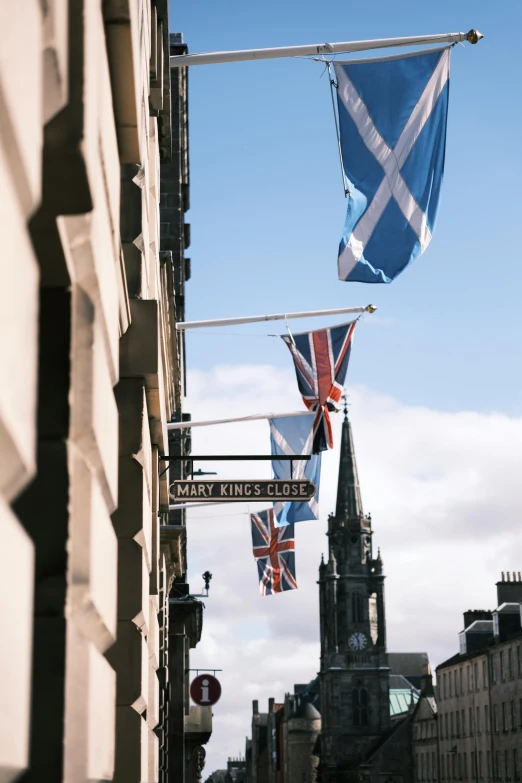 two flags on a pole in front of buildings