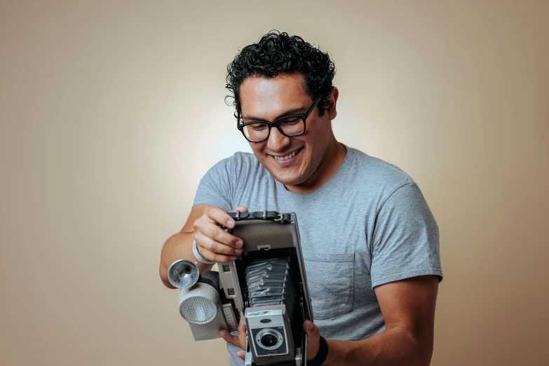 a man with glasses holding an old fashioned camera