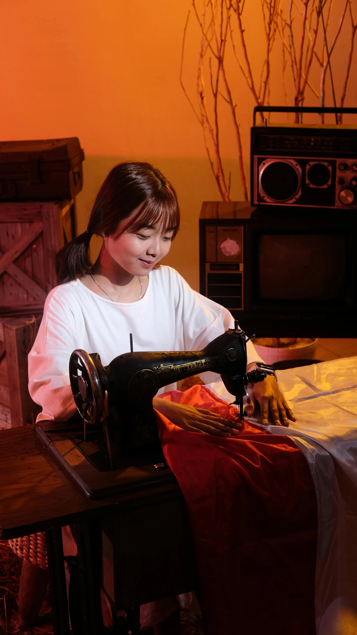 a woman sitting in front of a table using a sewing machine