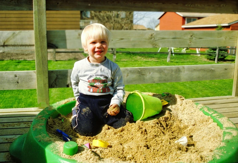 a little boy playing in a garden filled with sand