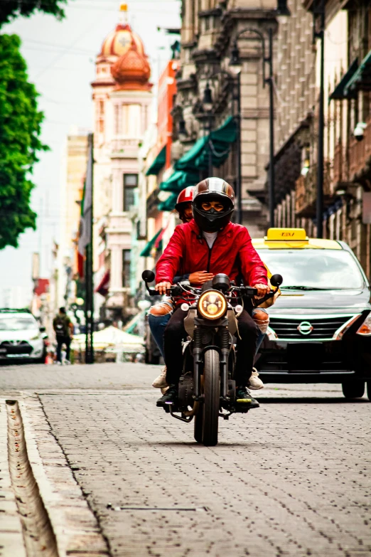 man on a motorcycle in front of cars and taxis