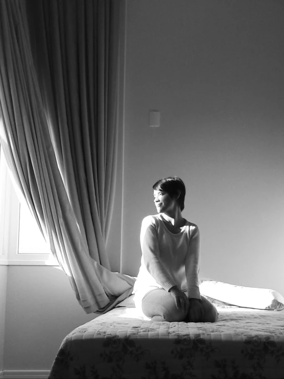 a woman sits on the edge of her bed