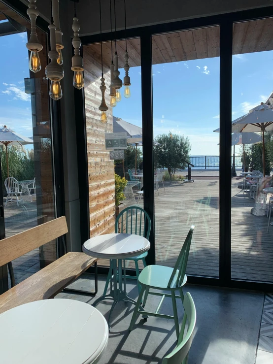 three tables sitting in front of large window next to umbrellas