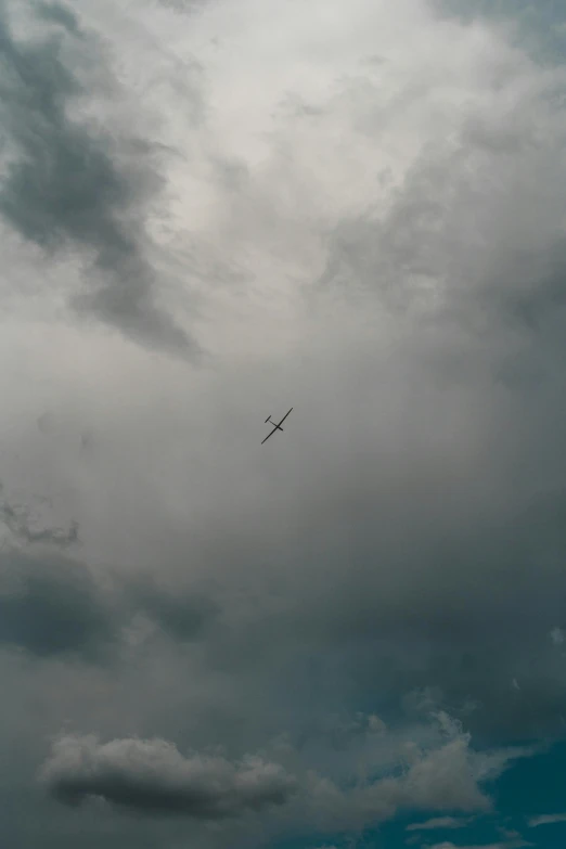 an airplane flying under a grey and cloudy sky