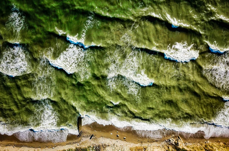 an overhead view of the green water on a beach