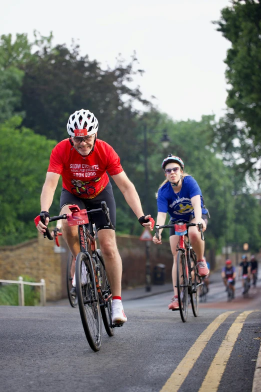 two cyclists one on the other is riding down a street