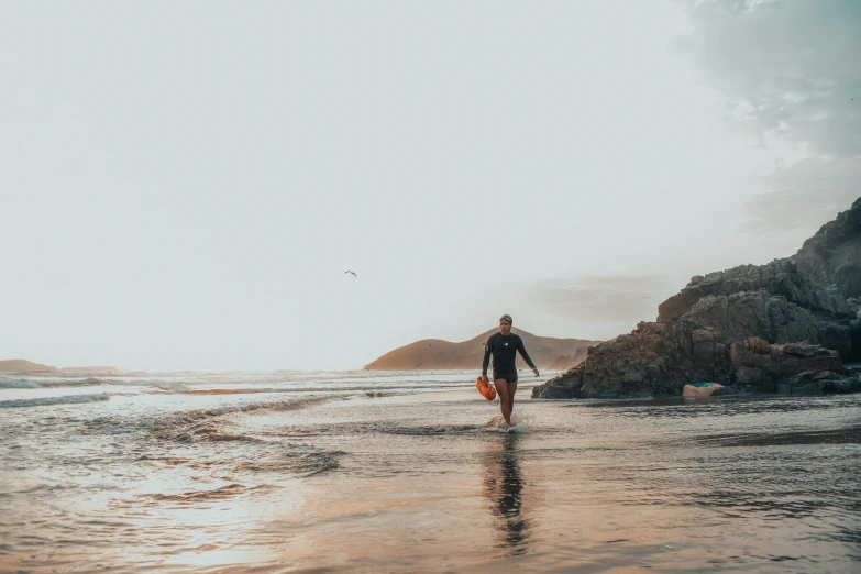 a person standing on top of a beach next to a body of water