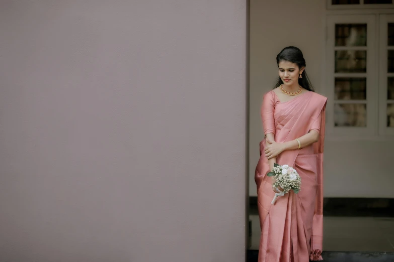 a woman in pink sari standing by the wall