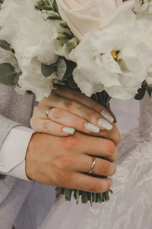 the bride is holding her grooms hands with wedding rings