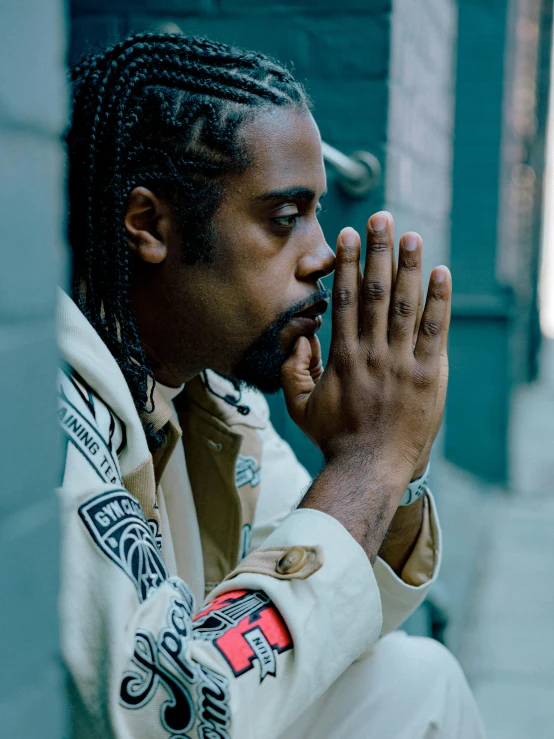 a man in a jacket sitting on the sidewalk