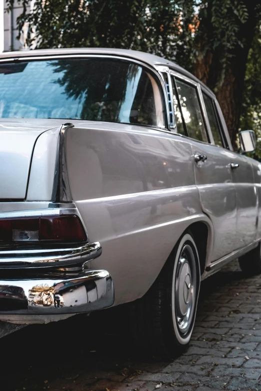 a old car sits in a street near a tree