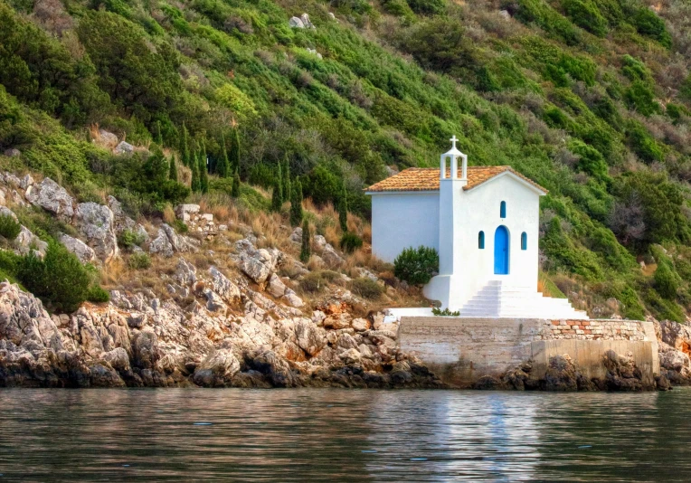 a building on a hill next to a body of water