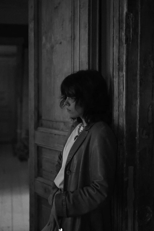 a woman leaning against the wall, in a dark room